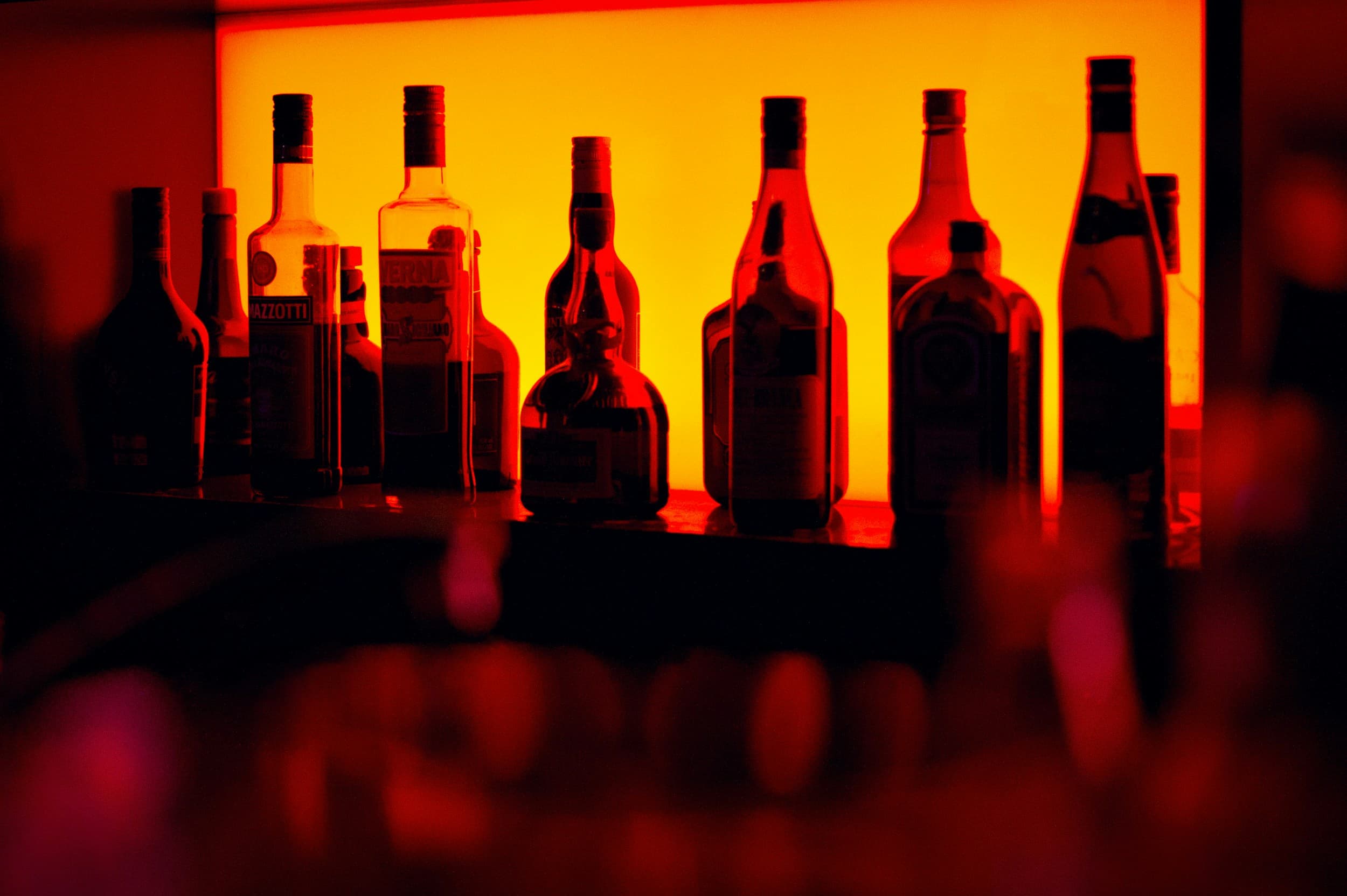 Des bouteilles d'alcool dans un bar avec lumière rouge